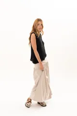 Pollera larga de corte evasé en color arena, con detalle de costura horizontal y frunces en la parte inferior que le otorgan volumen y movimiento.