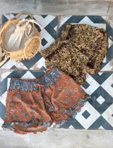 Short de seda con elástico fruncido en la cintura y volado en el ruedo. Presenta un estampado vibrante en tonos rojo/bordó y turquesa con motivos florales o arabescos.