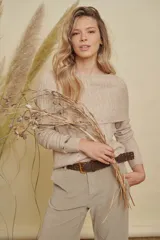 Buzo tejido de punto en color beige jaspeado, con cuello amplio versátil que permite usarlo con hombros descubiertos o como cuello tipo buche, y mangas largas.