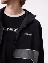 Rompevientos Rusty con cierre frontal, capucha y diseño de bloques de color en gris y verde militar. Cuenta con puños elásticos y logo de la marca en el pecho.