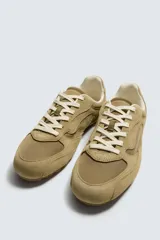 Zapatilla de estilo retro con cordones, confeccionada en una combinación de piezas de tela y cuero con acabado de gamuza. Cuenta con suela dentada en contraste.