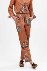 Pantalón largo color marrón con estampado de leopardos alados y constelaciones.