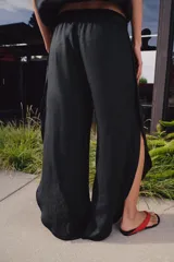 Pantalón de tiro medio confeccionado en lino, con cintura elástica ajustable mediante cordones. Presenta un diseño de pernera ancha con bajo redondeado y aberturas laterales.