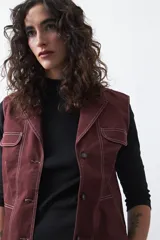 Chaleco de estilo utilitario color bordó con pespuntes blancos a contratono. Presenta solapas, cierre frontal con botones, bolsillos delanteros y un diseño estructurado.