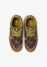 Championes urbanos Satorisan modelo Chacrona, confeccionados en cuero marrón con detalles en gamuza, cordones amarillos y suela de goma con efecto salpicado y detalles en verde.