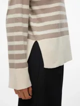 Sweater de punto con diseño de rayas horizontales en tonos beige y crema, cuello alto y mangas largas con puños anchos. Presenta un corte holgado y tejido de tacto suave.