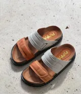 Sandalias de cuero color suela con doble tira, una ancha color suela y otra blanca con ajuste de velcro.