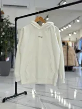 Canguro oversize de color beige claro con capucha, mangas largas y puños elastizados. Presenta un diseño gráfico en la espalda con el texto 'Creative Thinking' en tipografía cursiva negra sobre un fondo de letras grandes en tono rosado.