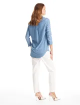 Blusa de lyocell color azul con efecto denim, cuello camisero con solapa y escote en V con cierre de un botón. Presenta mangas largas con terminación doblada y ruedo redondeado.