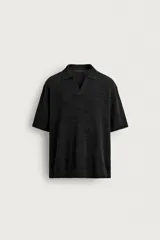 Polo de punto color negro con textura irregular, cuello solapa con abertura frontal, manga corta y acabados en rib, de corte relaxed fit.