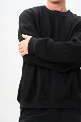 Buzo negro de corte amplio con cuello redondo y mangas largas.