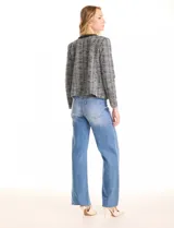 Chaqueta de tweed en tonos blanco y negro, con cuello redondo y abertura frontal. Presenta detalles de cinta con cadena en el cuello y en los bolsillos delanteros. Con forro interno.