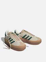 Championes Adidas Gazelle Bold para mujer, color beige con detalles en verde oscuro y suela de goma marrón de triple plataforma.