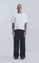 Pantalón técnico negro de silueta oversize, con cintura elástica, bolsillos cargo laterales y un cinturón de cinta con hebilla de plástico.