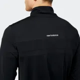 Remera deportiva New Balance de manga larga y cuello alto con cierre parcial, color negro, con logo NB reflectante en el pecho.