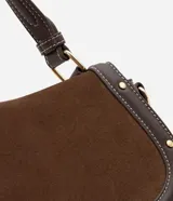 Cartera bandolera de tamaño mediano con cuerpo frontal en gamuza y laterales rígidos. Cuenta con asa corta superior, correa larga ajustable y desmontable, y bolsillo trasero. Presenta detalles metálicos en los bordes.