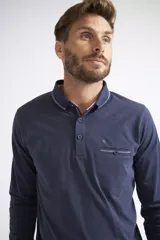 Remera polo de manga larga para hombre, con cuello clásico, cierre frontal de tres botones y bolsillo en el pecho con detalle de botón y costuras decorativas. Presenta un pequeño logo bordado sobre el bolsillo.