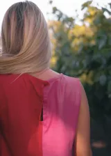 Vestido corto sin mangas con diseño bicolor, presentando una mitad en color rojo y la otra en color violeta. Posee un corte recto y holgado con cuello redondo.