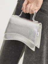 Cartera tipo bandolera pequeña, color plateado metalizado, con solapa superpuesta y correa fina ajustable.