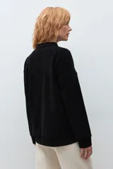 Sweater de pana color marrón con cuello polo y cierre frontal parcial. Presenta un diseño de corte holgado, mangas largas con puños elásticos y textura acanalada.
