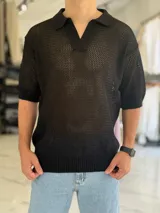 Chomba tejida color negro de punto calado, con cuello polo y escote en V, de manga corta y corte oversize.