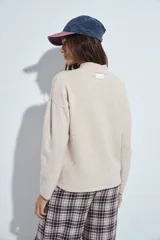 Sweater de punto gris con cuello a la base y diseño de trama geométrica en relieve. Presenta un calce relajado con mangas largas y puños tejidos.