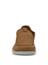 Mocasin de cuero color tostado con costuras visibles y suela de poliuretano blanca. Presenta un diseño de punta redonda y estilo slip-on.