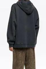 Hoodie de algodón color negro con efecto lavado, corte oversize y capucha con cordones ajustables. Presenta un estampado gráfico frontal con paisaje, lobos y rayos, junto con el logo de la marca.