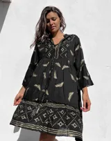 Túnica corta negra con estampado dorado de hojas y motivos geométricos, escote en V y mangas acampanadas.