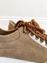 Championes de cuero color visón con cordones marrones, suela blanca y base color caramelo.