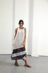 Vestido midi tejido en punto canalé negro con detalles en lurex plateado. Presenta calado artesanal en el ruedo, abertura lateral y etiqueta de cuero en la parte trasera del cuello.