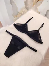 Conjunto de lencería compuesto por un corpiño triangular de microtul transparente con detalles de encaje en las copas y una tanga regulable de elástico ancho.