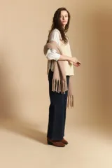Chaleco de tejido de punto en color crema, con cuello alto y diseño acanalado. Presenta una silueta relajada con aberturas laterales.