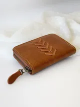 Billetera pequeña de cuero color marrón con cierre metálico y diseño de espiga. Incluye monedero interno.