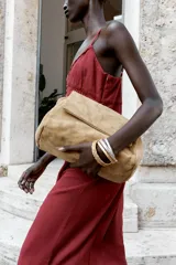 Bolso de hombro confeccionado en piel de ante color tostado, con diseño acolchado mediante pespuntes horizontales y verticales. Cuenta con una correa de cadena metálica dorada con refuerzo de piel y cierre mediante solapa con imán.