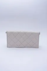 Cartera de cuero color marrón claro, con diseño capitoneado y cadena metálica plateada removible. Tiene ranuras interiores para tarjetas y documentos, y forro textil rojo.