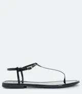 Sandalia baja negra de mujer con acabado en charol (verniz satinato). Diseño tipo thong (dedal) con tira fina que se une a una tira tobillera ajustable con hebilla metálica dorada.