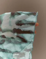 Vestido corto estampado con efecto animal print en tonos aqua y marrón, escote profundo en V cruzado y mangas largas anchas y acampanadas.