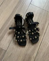 Sandalias negras de cuero vacuno con tiras y apliques de tachas doradas.