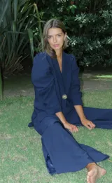 Blazer rojo de seda con cuello solapa, hombreras marcadas y un botón decorativo en forma de sol.