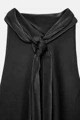 Top de cuello halter confeccionado en tela satinada, con diseño de espalda descubierta y bajo asimétrico.