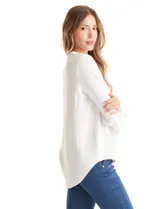 Blusa de color blanco con escote en V y cuello mao. Presenta mangas largas con presilla y botón para regular el largo, y un corte holgado con ruedo redondeado.