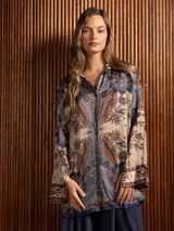 Camisa de seda de corte clásico y largo, con estampado paisley en tonos azules, marrones y beige. Presenta cuello camisero, cierre frontal con botones y mangas largas con puños rectos.