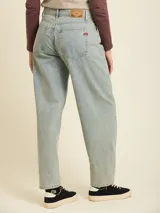 Jean de denim en corte balloon fit, con tiro medio y lavado claro. Presenta costuras laterales curvadas que definen su silueta amplia y relajada.