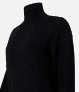 Suéter de manga larga confeccionado en tricot, con cuello alto y diseño de bordado de rombos en relieve. Presenta puños y ruedo acanalados.