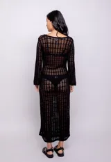 Vestido largo negro de tejido de punto calado, con escote redondo y mangas largas acampanadas.