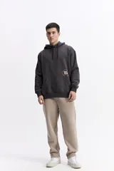 Canguro con capucha y cordones ajustables en color beige, con diseño de calce regular y estampado frontal pequeño.