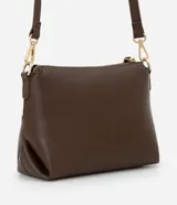 Cartera transversal pequeña color marrón, con la parte superior de gamuza y la inferior de cuero sintético. Tiene cierre de cremallera metálica dorada y asa larga ajustable y desmontable con mosquetones dorados.