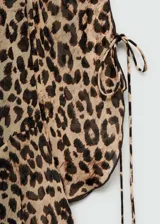 Vestido corto de tejido fluido y semitransparente con estampado animal print de leopardo. Presenta cuello redondo, diseño recto y mangas largas con detalle de lazo ajustable en los puños. Incluye forro interior.