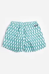 Short de baño celeste con estampado de hojas pequeñas en tonos verdes y blancos. Cuenta con cintura elástica con cordón ajustable, bolsillos laterales y un parche circular con logo en la parte inferior.